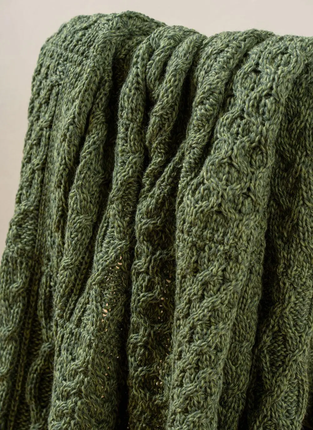 Close-up of dark green Aran throw draped across wooden chair